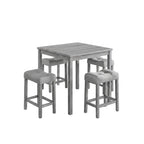 Gray dining table with four matching stools in a room with a plant and framed pictures on the wall.